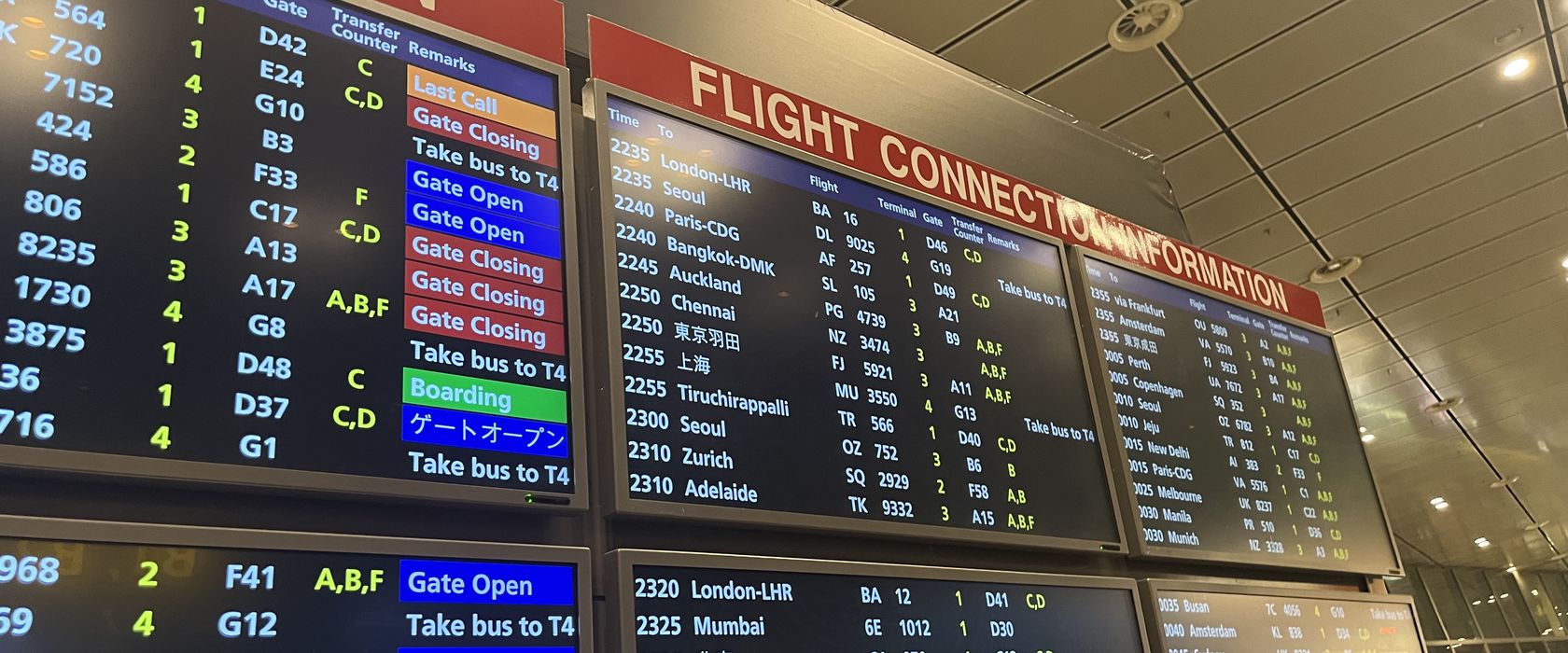 Airport flight connection boards listing departures to London, Seoul, Paris, Auckland and more.