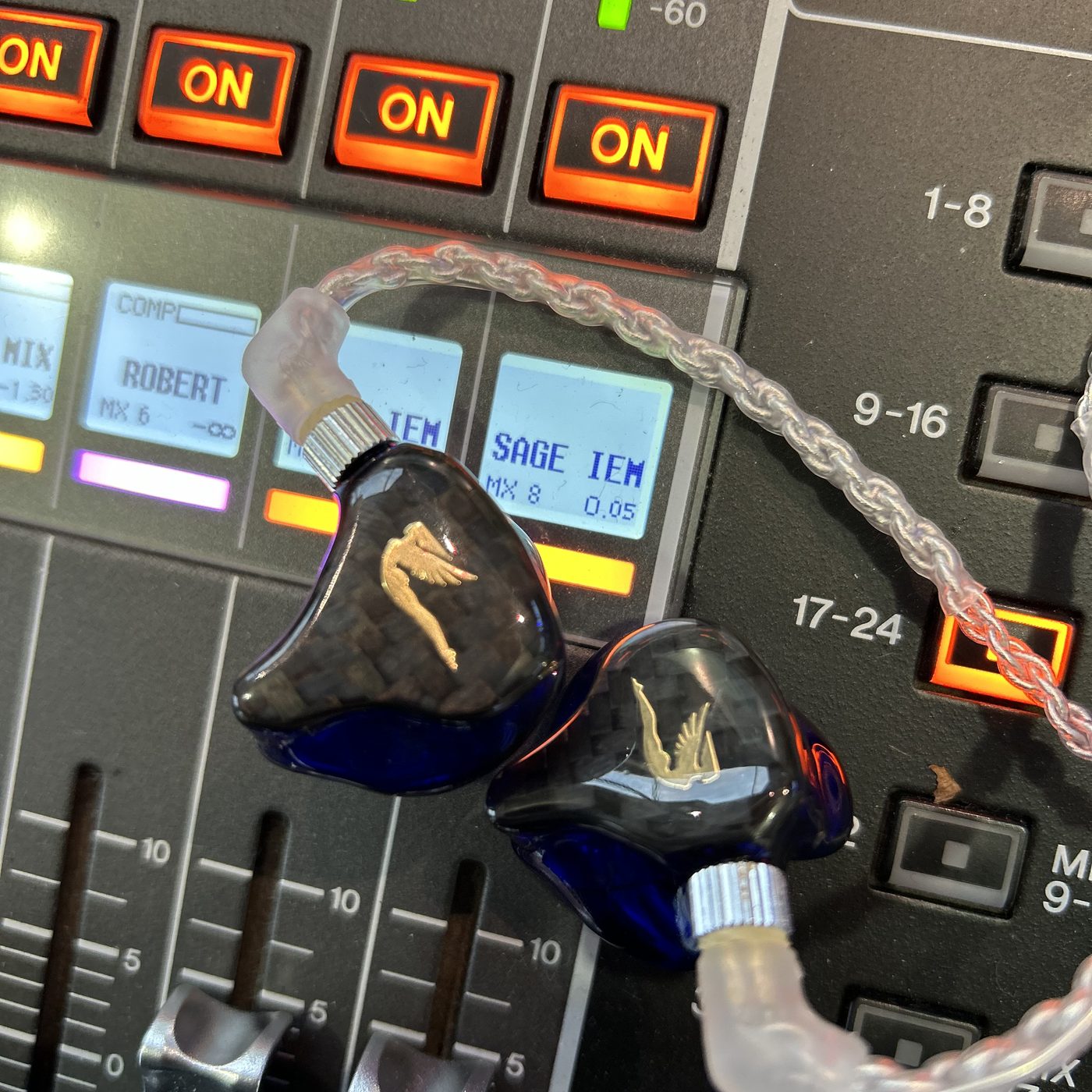 Custom in-ear monitors resting on a console, the scribble strip behind them reading SAGE IEM.