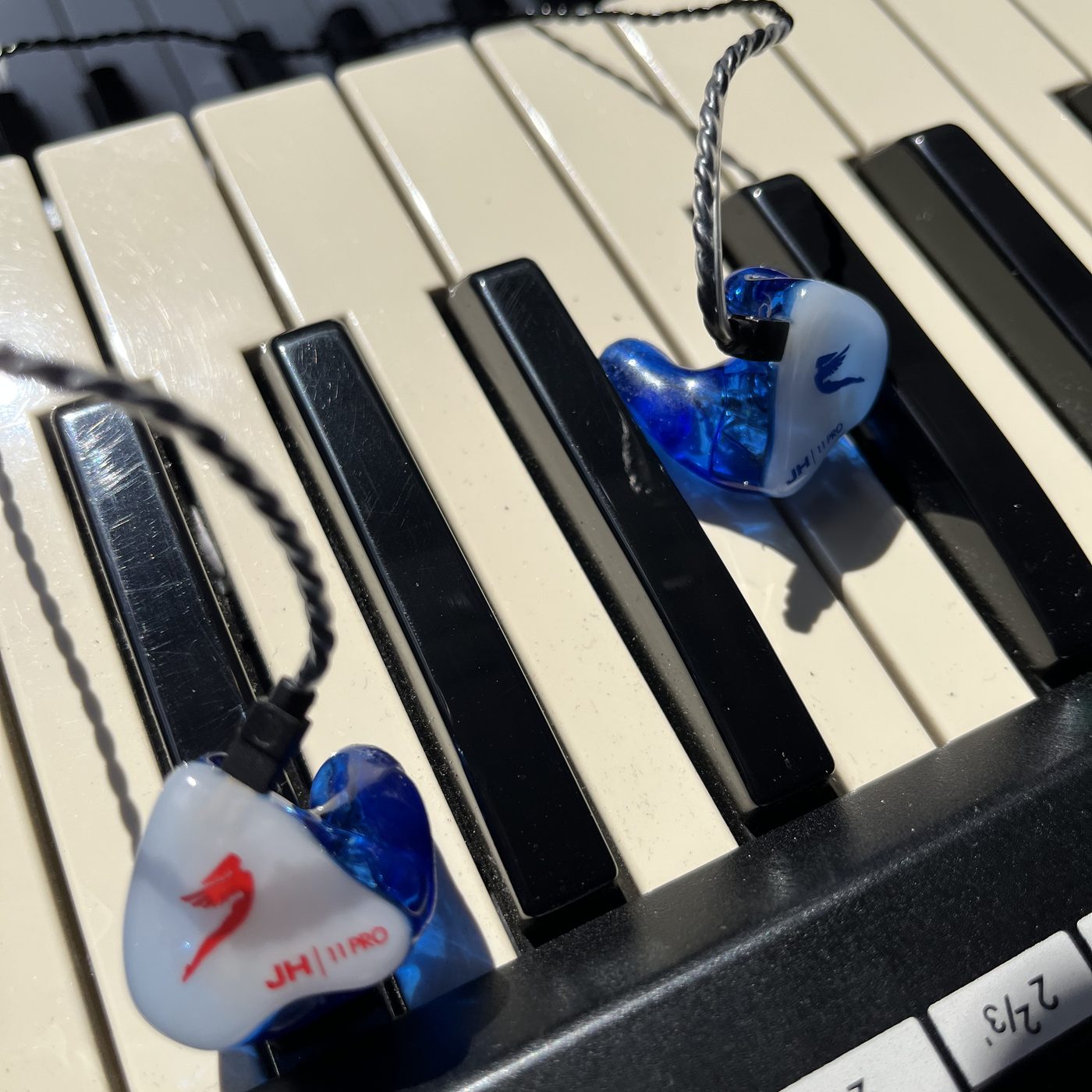 A pair of custom moulded JH Audio 11 Pro in-ear monitors resting on the keys of a stage piano.
